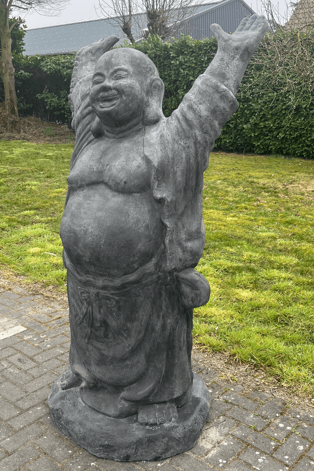 Stenen grote vrolijke boeddha voor in de tuin