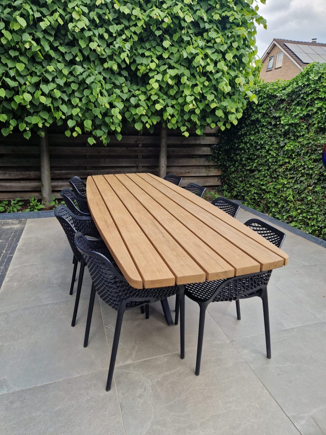 Buitentafel in stuiver vorm van Afrikaans eiken Fraké hout op maat op modern terras in Almelo Twente Buitentafel in stuiver vorm van Afrikaans eiken Fraké hout op maat op modern terras in Almelo Twente