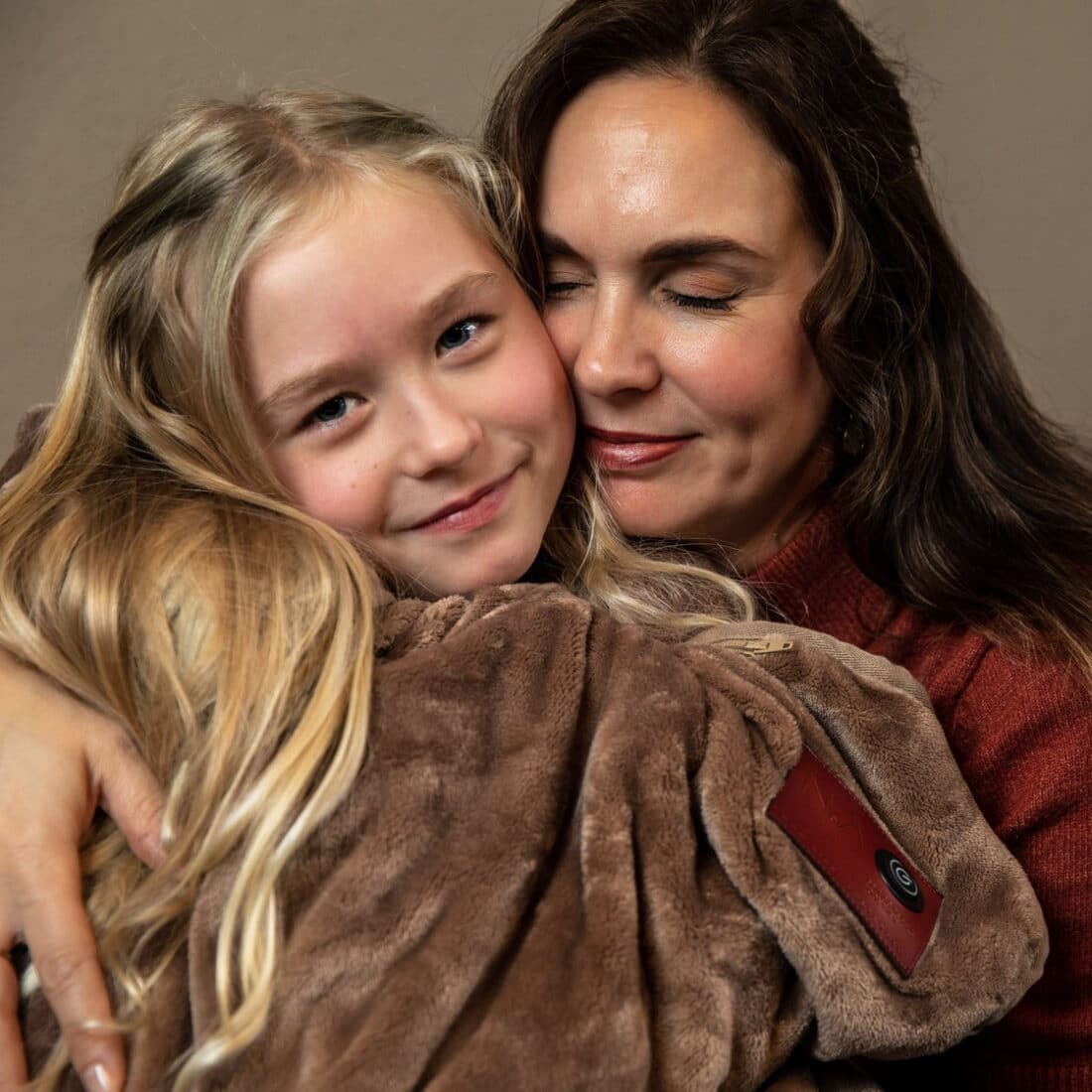 moeder en dochter samen onder een zachte infrarood warmtedeken in de kleur taupe moeder en dochter samen onder een zachte infrarood warmtedeken in de kleur taupe