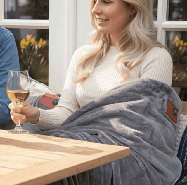 Une femme utilise une couverture chauffante infrarouge grise sur une terrasse