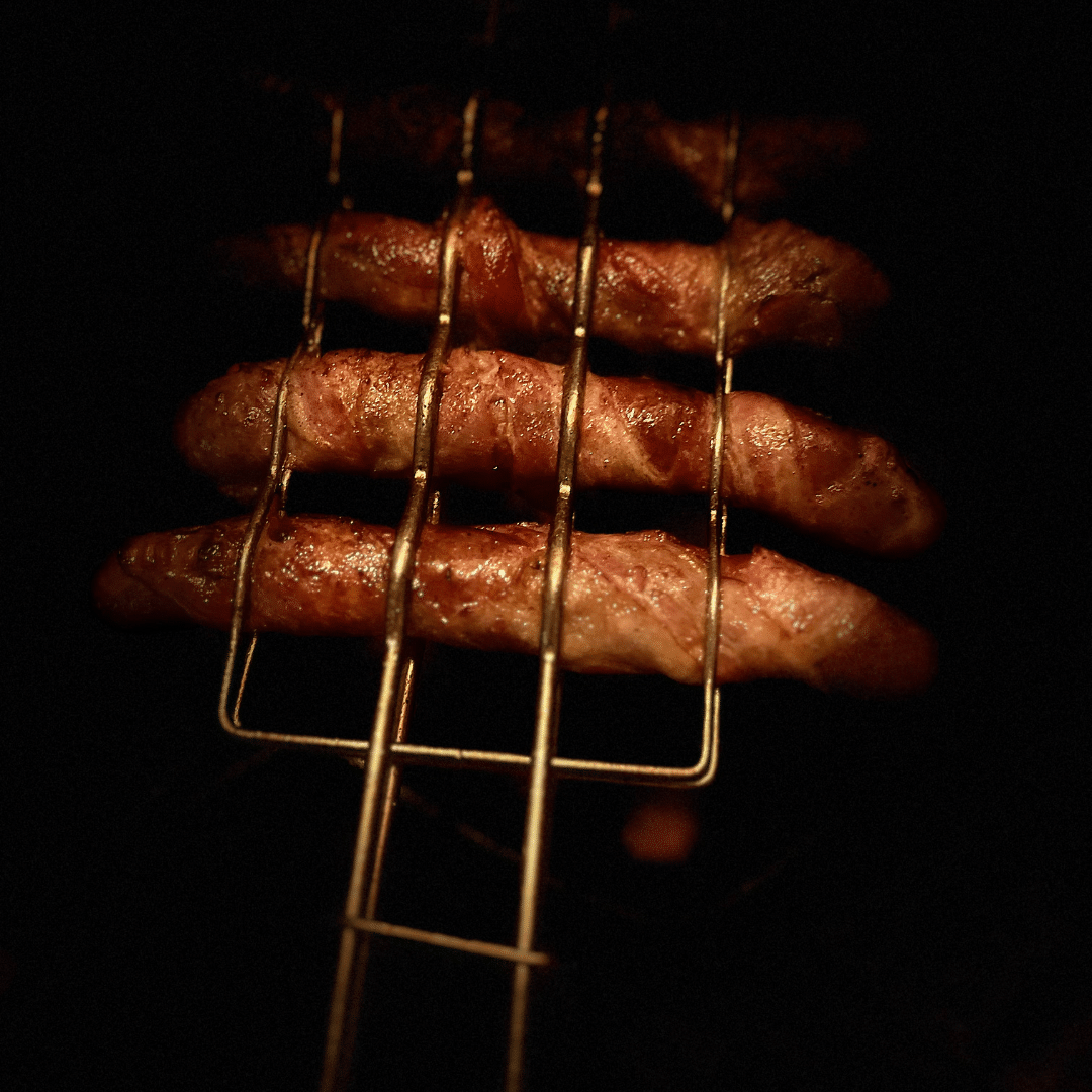 grillrooster voor worstjes met merquez worstjes omwikkelt met ontbijtspek